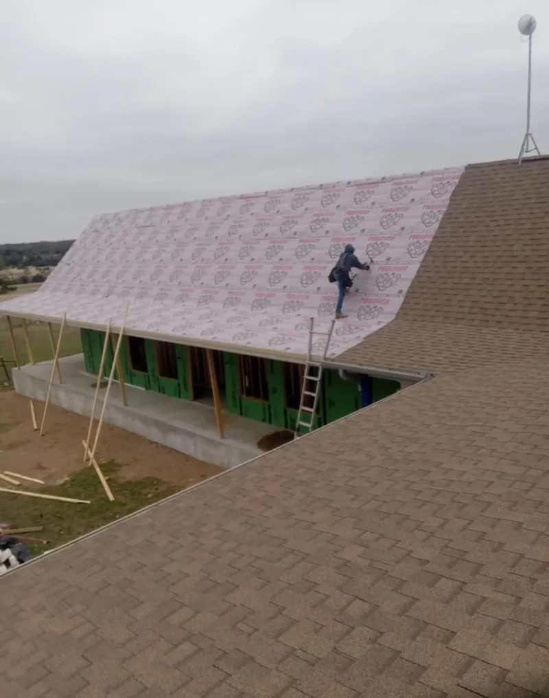 Worker preparing underlayment for a metal roof installation in Ocean Pointe